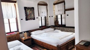 A neatly made bed with white linens and towels, a wooden headboard, and a painting on the wall. - Silver Hill Guesthouse (Gjirokastër)