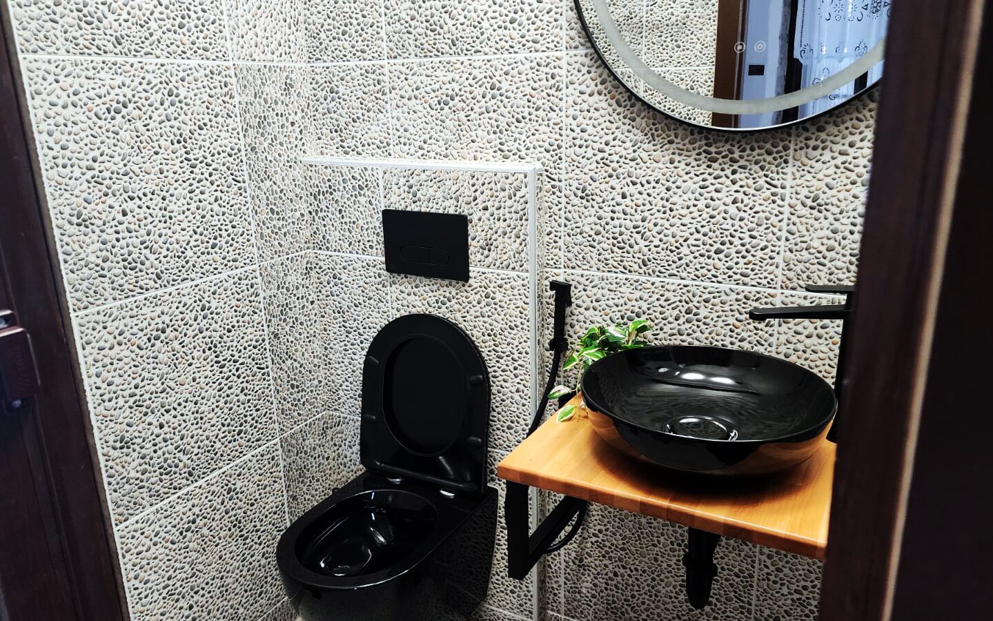 Un baño pequeño con un inodoro, un espejo y un estante con un cuenco negro.