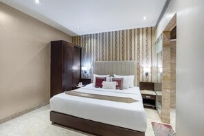 Une chambre d’hôtel moderne, dotée d’un grand lit, d’une armoire, d’une table de chevet et d’un miroir.