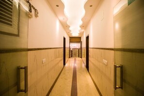Un couloir d’hôtel avec un sol en marbre, un éclairage encastré et un mur décoré d’un motif au fond.