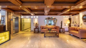 Eine geräumige Lobby mit Holzbalkendecke, einer Rezeption, einem Sofa und einem Couchtisch.