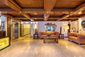 Um hall amplo com teto de madeira, balcão de recepção, sofá e mesa de centro.