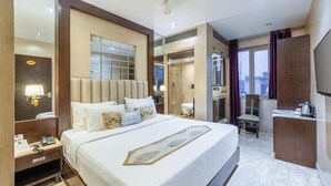 Ein Hotelzimmer mit einem großen Bett, einem Schreibtisch mit Stuhl, einem Spiegel und Blick auf die Stadt durch das Fenster.