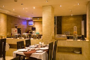 Ein Hotelrestaurant mit Marmorwänden, einem Buffet und gedeckten Tischen.