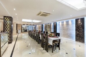Un vaste espace dédié à la salle à manger, avec une longue table, des chaises et un lustre.