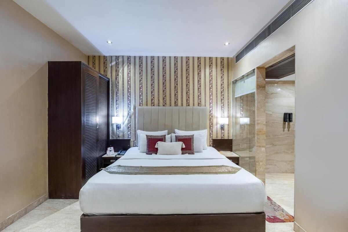Ein Hotelzimmer mit einem großen Bett, einem Holzschrank, einem Nachttisch und einem Spiegel.