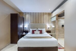 Ein Hotelzimmer mit einem großen Bett, einem Holzschrank, einem Nachttisch und einem Spiegel.