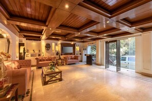 Uma sala de estar espaçosa com pé direito alto, janelas amplas e lareira.