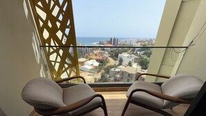 A balcony with two chairs and a view of the sea and buildings. - Luxury apartment with rooftop, games room, 5 min from the beach (Dakar)