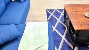 A living room with a blue sofa, a wooden coffee table, and a patterned rug.