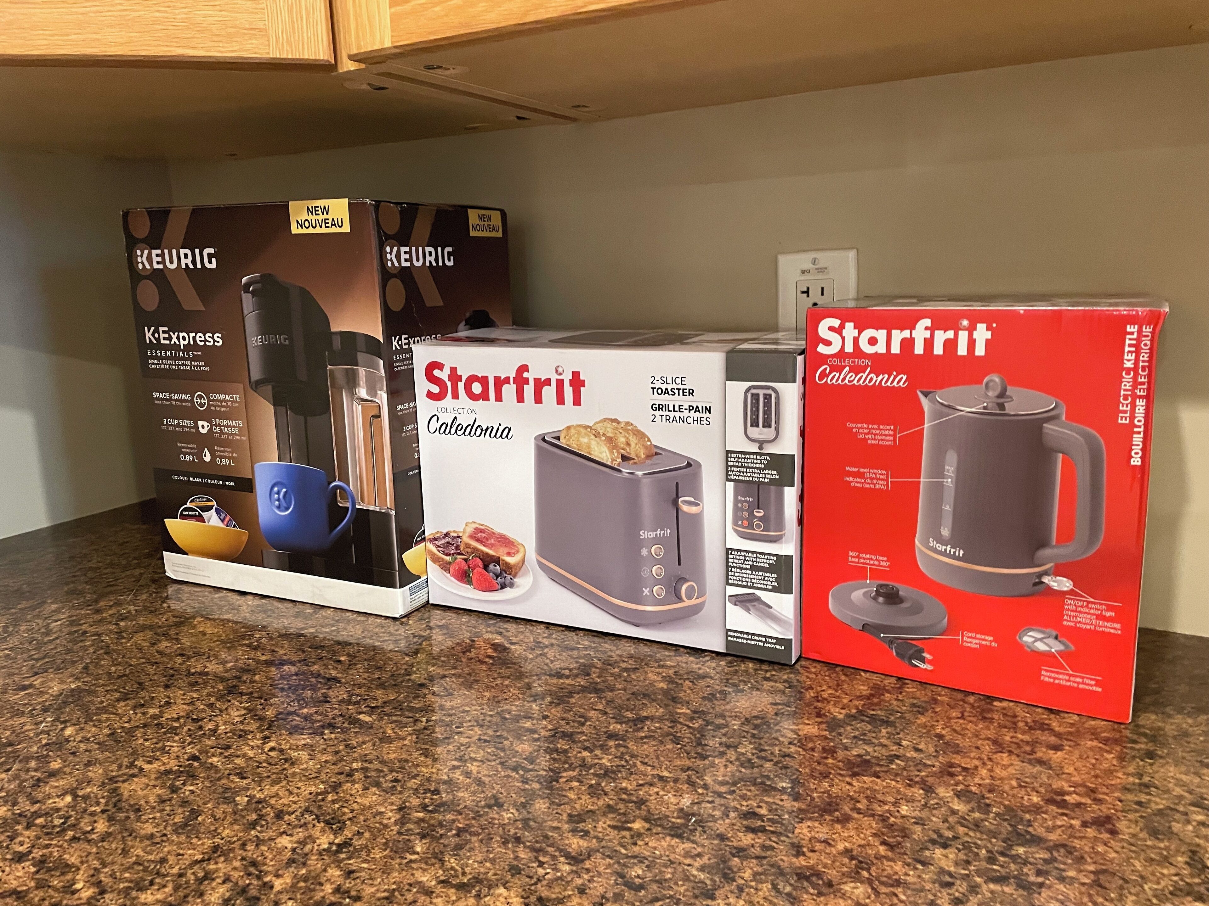 Drei Küchengeräte auf einer Arbeitsplatte: eine Keurig K-Express Kaffeemaschine, ein Starfrit Collection Catedonia Toaster und ein Starfrit Wasserkocher.