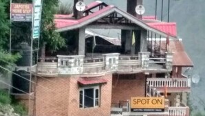 Un edificio de varios pisos con techo rojo, balcones y un letrero que indica un lugar en la propiedad.