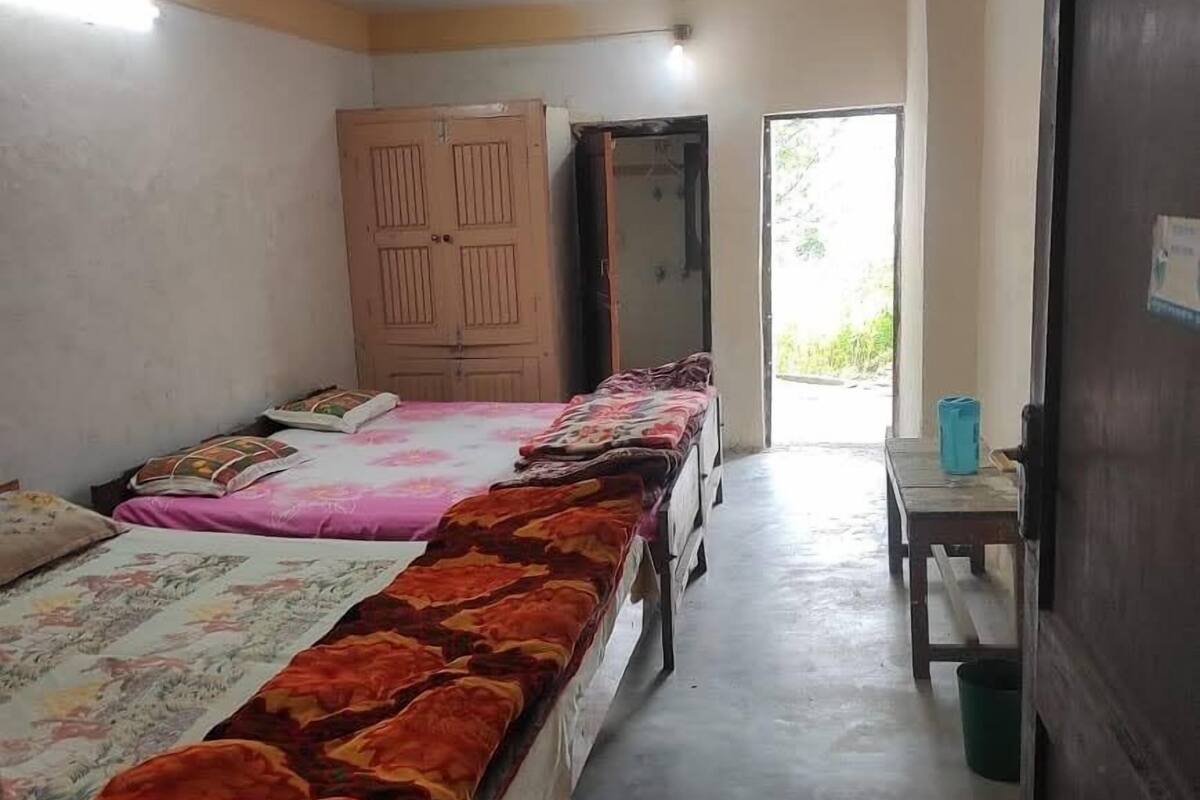 Une chambre de dortoir avec deux lits, une armoire et une petite table avec un seau.