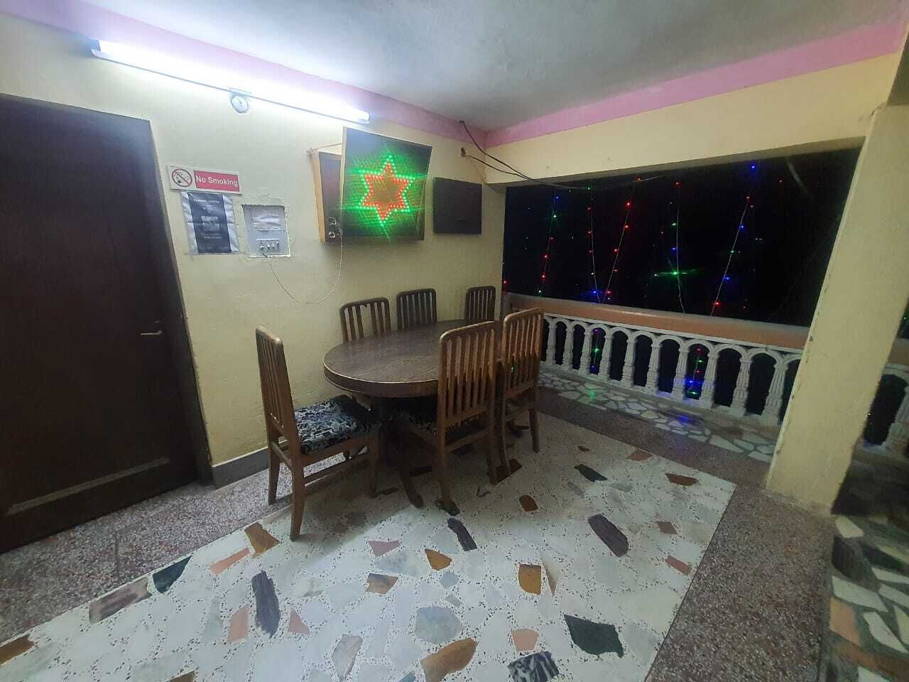 Un comedor con una mesa redonda y sillas, un cartel de 'No Smoking', una estrella decorativa y un balcón con guirnaldas de luces.