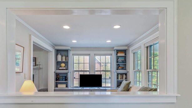 A room with a built-in TV, bookshelves, and a window with a view. - Saskadena Lodge with Game Room, near Ski Hill (Pomfret)