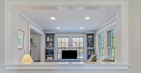A room with a built-in TV, bookshelves, and a window with a view.