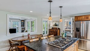 A kitchen with a large island, built-in shelves, a refrigerator, and pendant lighting. - Saskadena Lodge with Game Room, near Ski Hill (Pomfret)