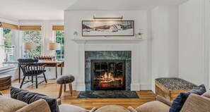 A living room with a fireplace, wooden furniture, and a painting above the mantel.