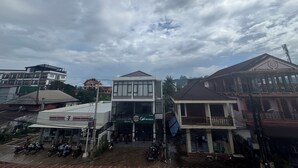 A 7-Eleven convenience store with a cafe in front, surrounded by multi-story buildings. - Vang Vieng Golden Lotus Hotel (Vang Vieng)