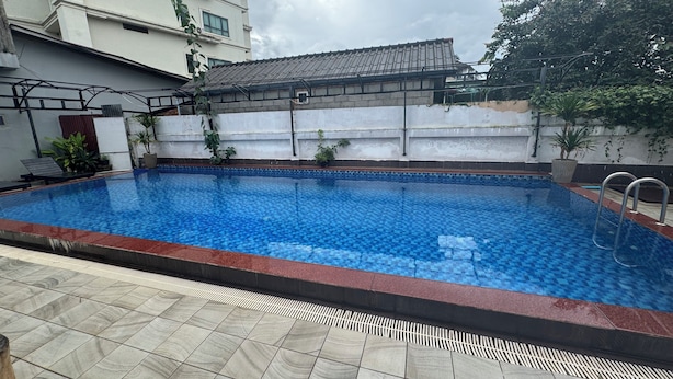 A rectangular outdoor swimming pool with a tiled edge and a metal ladder. - Vang Vieng Golden Lotus Hotel (Vang Vieng)