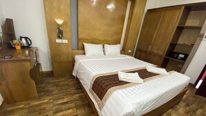 A neatly arranged hotel room with a wooden bed, a desk with a kettle, and a wardrobe. - Vang Vieng Golden Lotus Hotel (Vang Vieng)