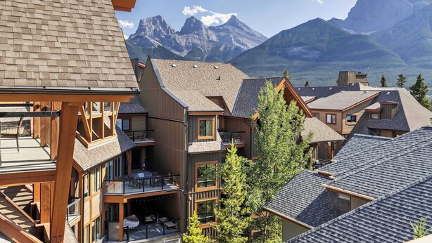Un immeuble à plusieurs étages, doté d’une façade en bois et de nombreux balcons. L’édifice présente un style architectural moderne, avec de grandes fenêtres et un toit plat.
