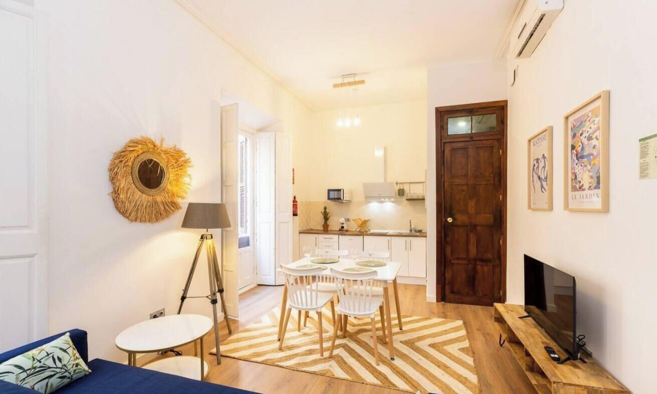 Un espace de vie compact comprenant un coin repas, une kitchenette et un téléviseur posé sur un meuble en bois.