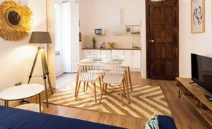 A living room with a sofa, a coffee table, a TV, and a dining area with chairs and a table. - Strachan 1 Trip Malaga - Beautiful studio in the heart of Malaga. (Málaga)