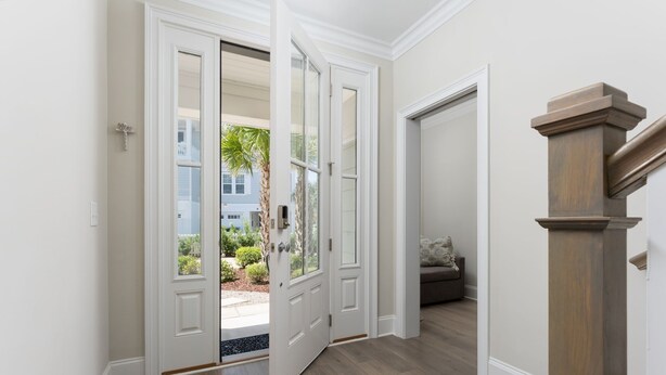 A hallway with wooden flooring, white walls, and a wooden staircase. - True North - Ocean Bliss Retreat in Kure Beach (Kure Beach)