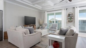 A spacious living room with a flat-screen TV, two sofas, a coffee table, and a ceiling fan. - True North - Ocean Bliss Retreat in Kure Beach (Kure Beach)