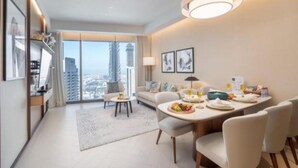 Ein modernes Hotelzimmer mit Essbereich, einer Sitzecke und einem großen Fenster mit Blick auf die Stadt.