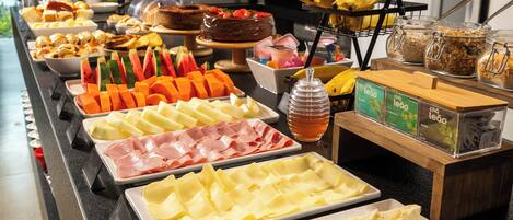 Un bufé con diferentes opciones de comida, incluyendo carnes, quesos, frutas y un pastel.
