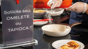 A sign with text in a foreign language, a person wearing gloves, a frying pan, and a plate with food.