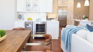 A modern kitchen with white cabinets, stainless steel appliances, and a dining area with a wooden table and leather chairs.