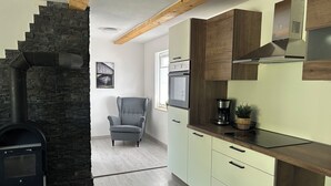 Une cuisine moderne avec une cheminée en pierre, des poutres en bois et des meubles de couleur claire.