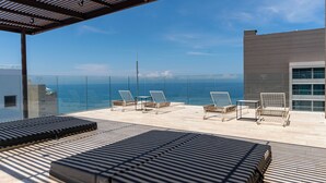 A rooftop terrace with sun loungers and a view of the ocean. - Apartamento SuiLoft 1313 Bello Horizonte (Santa Marta)