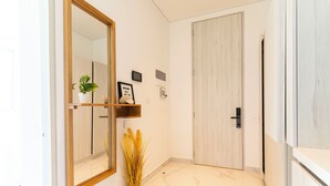 A hallway with a wooden-framed mirror, a potted plant, and a framed welcome sign. - Apartamento SuiLoft 1313 Bello Horizonte (Santa Marta)
