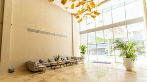 A spacious lobby with a large seating area, a potted plant, and a view of the outdoors through large windows. - Apartamento SuiLoft 1313 Bello Horizonte (Santa Marta)