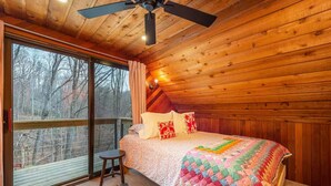A cozy bedroom with a large window, a ceiling fan, and a colorful quilt on the bed. - Mountain Dove Log Cabin Healing Retreat+Mtn Views+Walking trail (Weaverville)