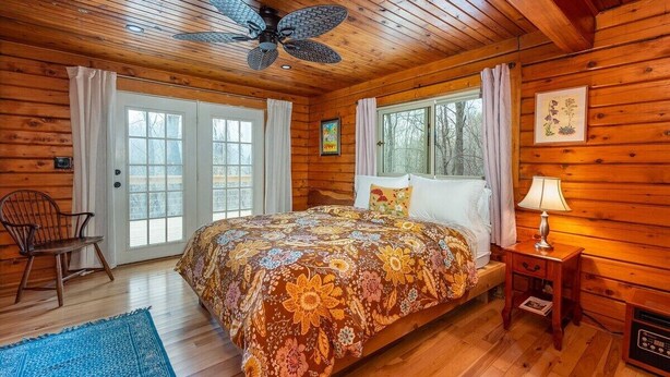 A wooden cabin bedroom with a bed, a chair, a nightstand, and a ceiling fan. - Mountain Dove Log Cabin Healing Retreat+Mtn Views+Walking trail (Weaverville)