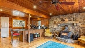 A cozy cabin interior with a stone fireplace, wooden ceiling, and a dining area with a bar. - Mountain Dove Log Cabin Healing Retreat+Mtn Views+Walking trail (Weaverville)