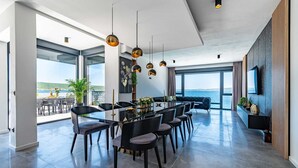 A modern dining area with a long table, black chairs, and pendant lights.