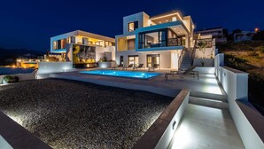 A modern two-story house with a swimming pool, outdoor seating, and a staircase leading to the upper level.