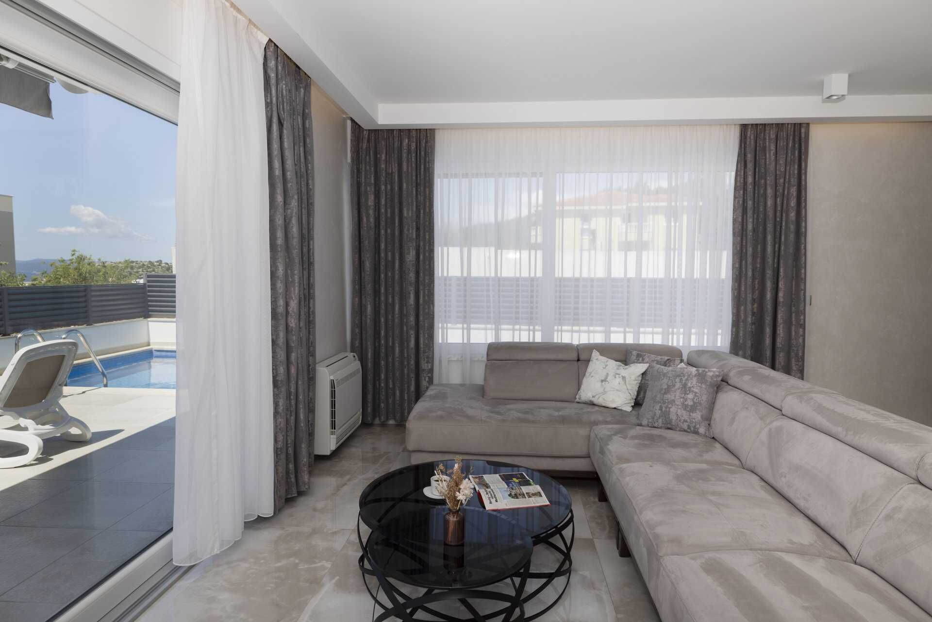 Un salon moderne avec un canapé, une table basse et un espace aménagé près de la piscine, comprenant une chaise et une piscine.