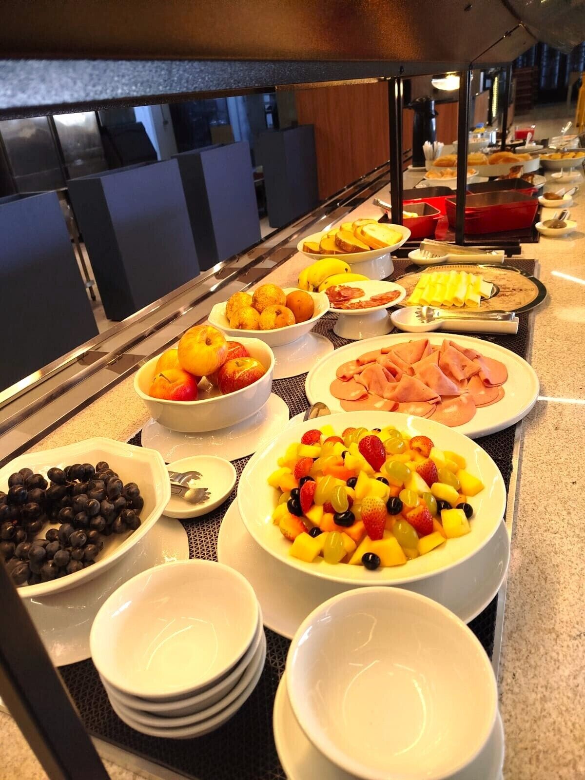 A buffet with various food items including fruits, meats, and cheeses.