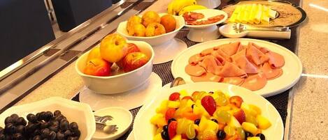 A buffet with various food items including fruits, meats, and cheeses.