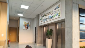 A modern lobby with a large artwork depicting a family, a reception desk, and a seating area with leather chairs.