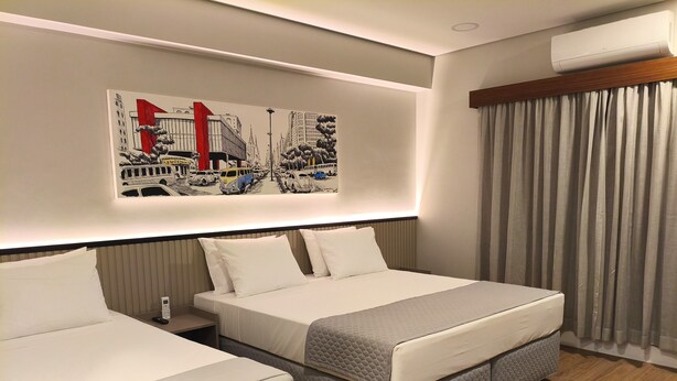 A hotel room with two beds, a cityscape artwork on the wall, a telephone, and a window with curtains. - Hotel 28 (Embu das Artes)