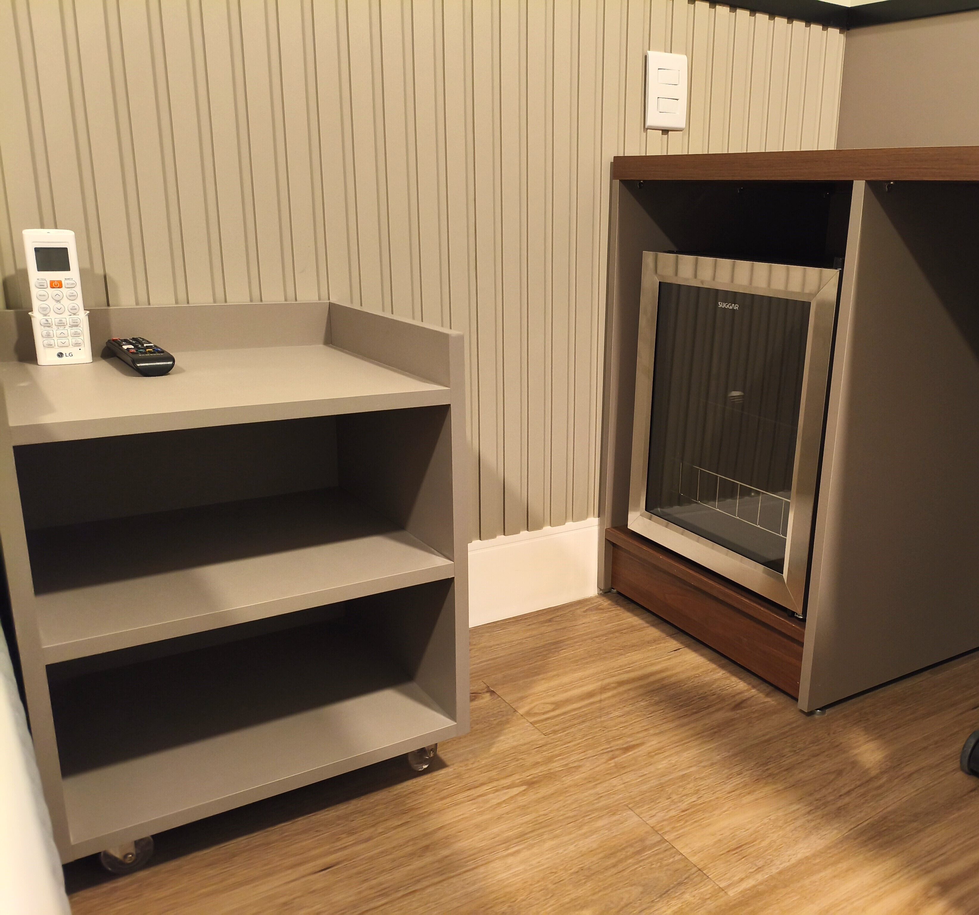 A room with a grey shelving unit, a remote control, and a television on a stand.