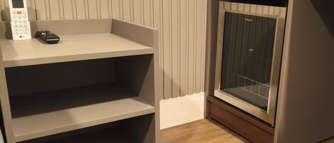 A room with a grey shelving unit, a remote control, and a television on a stand.